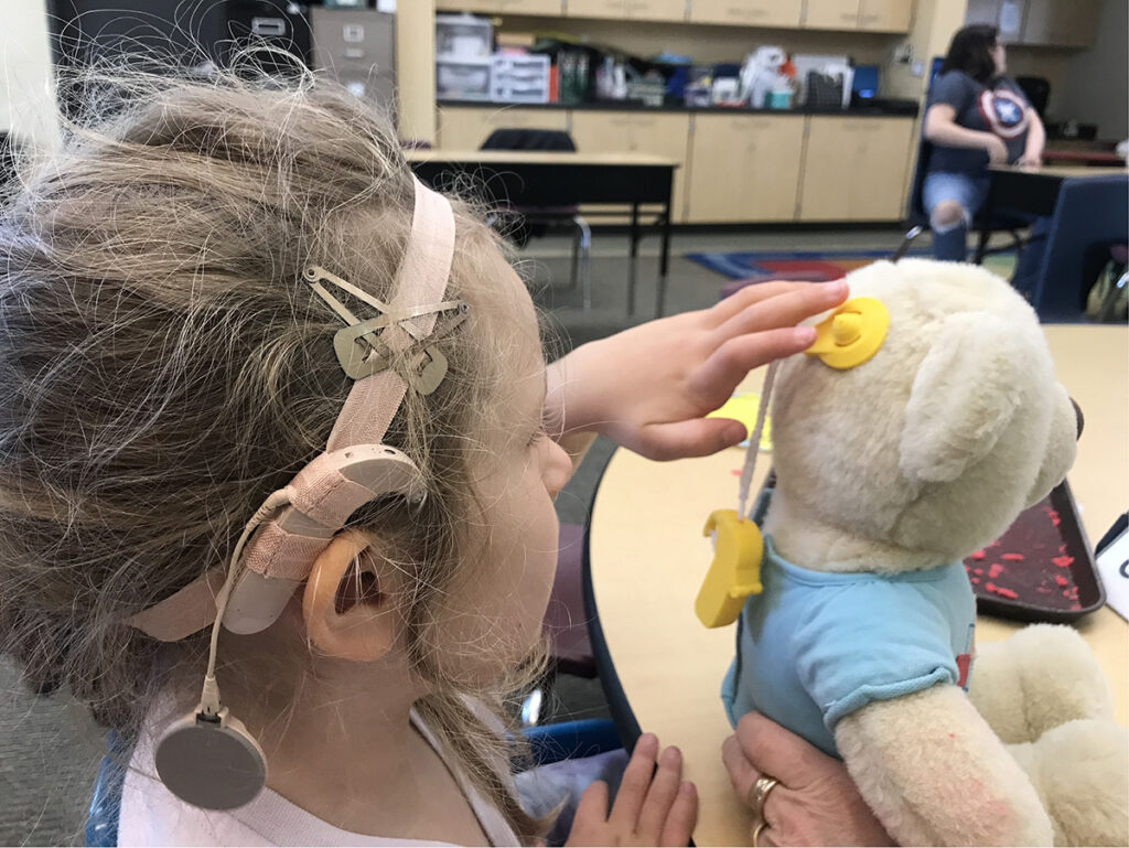 Deaf student learning to place hearing aids