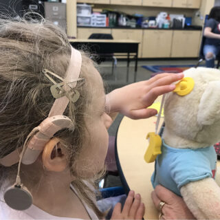 Deaf student learning to place hearing aids